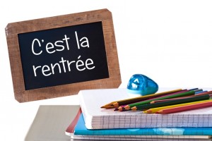 C'est la rentree (meaning Back to school) written on black chalkboard with school supplies